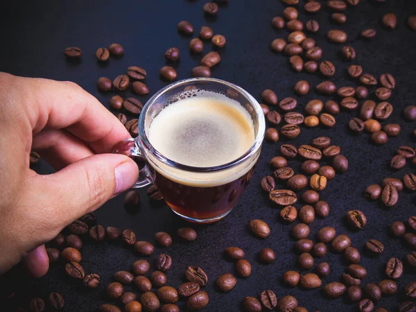 Bir adamın eli bir fincan espresso ile karışık kahve çekirdeklerini bir arada tutar. kahve havası