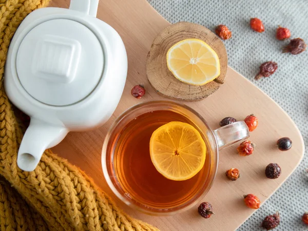Sonbahar sakin bir hayattır. Beyaz çaydanlık, fincanda çay dilimlenmiş limon ve kurumuş gül kalçası.
