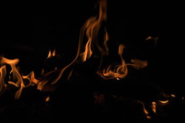 Geceleri odun yakmak. Dağlardaki turistik kamplarda kamp ateşi. Alevler soyut arka planda kıvılcımlar saçıyor. Dışarıda ızgara yapıyorum. Cehennem ateşi elementi. Yakıt, güç ve enerji