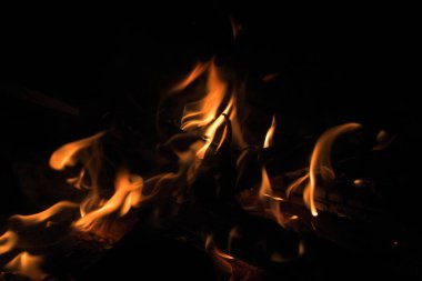 Geceleri odun yakmak. Dağlardaki turistik kamplarda kamp ateşi. Alevler soyut arka planda kıvılcımlar saçıyor. Dışarıda ızgara yapıyorum. Cehennem ateşi elementi. Yakıt, güç ve enerji