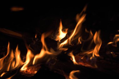 Geceleri odun yakmak. Dağlardaki turistik kamplarda kamp ateşi. Alevler soyut arka planda kıvılcımlar saçıyor. Dışarıda ızgara yapıyorum. Cehennem ateşi elementi. Yakıt, güç ve enerji