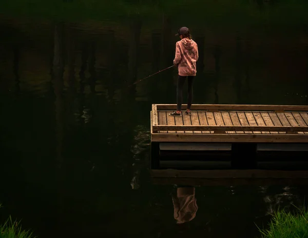 Sabah erken saatlerde genç bir kız tek başına bir rıhtıma balıkçılık yapıyor. Hala çoğunlukla ağaçların gölgesinde ve kendisi gölün karanlık sakin suyuna yansıtmaktadır. Döküm ve onun cazibesini alma o beklenen ısırık üzerinde yoğunlaşır.