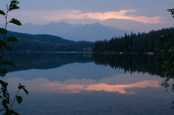 stock image Very peaceful morning sunrise with the base of the clouds highlighted by the sun and reflected on the calm lake.  A tranquil scene, projecting calmness and reflection.