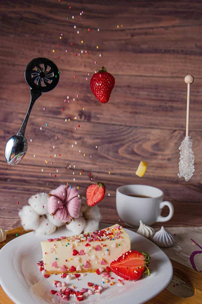 flying food tea drinking donut in the air on a wooden background with colored sprinkling cake cheesecake with fresh berries strawberries