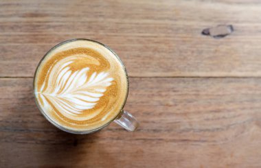 Ahşap masada sıcak kahve latte sanat Fincan.