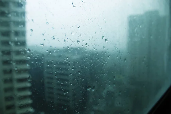 Kleine druppels water spatten tegen het raam op een koude regenachtige ochtend in de stad — Stockfoto