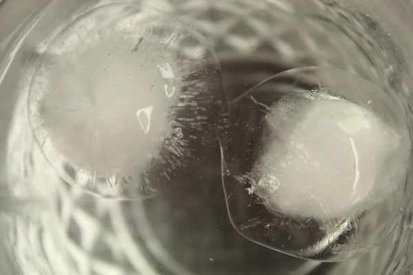 Close up shot of round-shaped ice cubes melting in a transparent glass of water — Stock Photo, Image