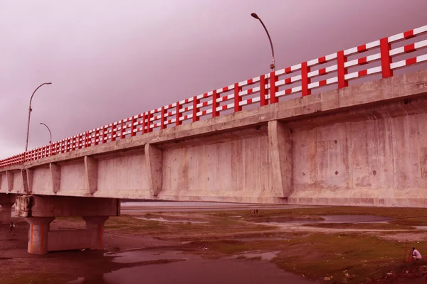 Long Big concrete bridge.An elevated concrete highway spanning across a Dark cloudy sky.view under the grey briage in the city.Modern construction engineering for road.