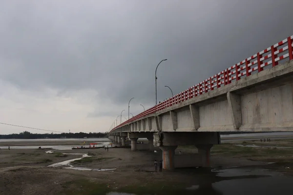 Uzun beton köprü. Karanlık bulutlu bir gökyüzü boyunca uzanan yüksek beton bir otoyol. Şehirdeki gri kirişin altındaki manzara..