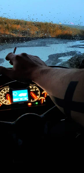 Hand van een man met een sigaret aan het stuur. — Stockfoto