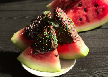 Çikolata jöleli karpuz. Olgun karpuz, siyah ahşap bir masada. Bir çocuk için tatlı. Ekran koruyucusunda yemek olan fotoğraf. Karpuz kapat..