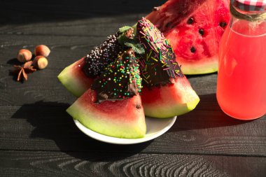 Çikolatalı karpuz tatlısı, beyaz tabakta. Cam bir tabakta karpuz suyu, siyah ahşap bir masada. Anason ve ceviz, görsel beslenme için..