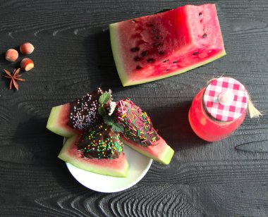 Çikolatalı karpuz, tatlı. Siyah arka planda cam bir şişede karpuz suyu. İçki, nane ve anason için baharatlar..