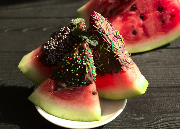 Çikolata jöleli karpuz. Olgun karpuz, siyah ahşap bir masada. Bir çocuk için tatlı. Ekran koruyucusunda yemek olan fotoğraf. Karpuz kapat..