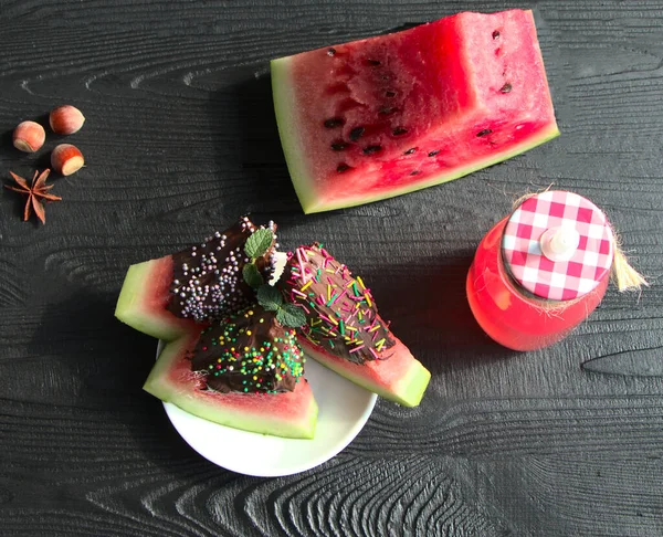 Çikolatalı karpuz, tatlı. Siyah arka planda cam bir şişede karpuz suyu. İçki, nane ve anason için baharatlar..