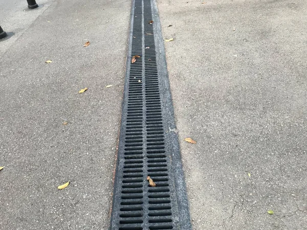 排水目的のために住宅街の場所でアスファルト道路を渡って黒の色のエポキシ塗装床排水チャンネルのグレーティング — ストック写真