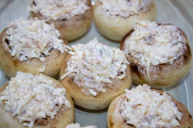 Peynir, mantar sapı ve soğanla doldurulmuş mantar dolması. Fırın kabında. Öncesi ve sonrası.