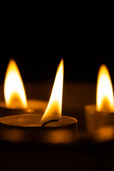 three candles in the dark, close up.