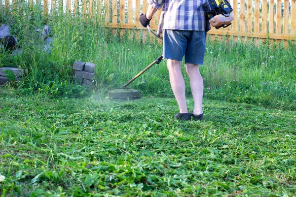 Чоловік косить зелену траву тримером — стокове фото