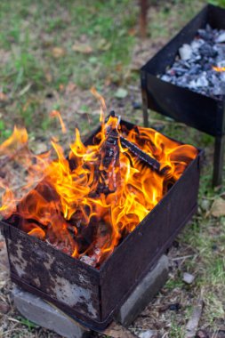 Metal bir ızgarada ateş yanıyor. Yakın mesafeden büyük, parlak bir ateş alevi. Açık hava eğlencesi. 6
