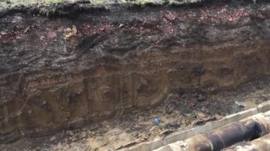 Isıtma tesisatı borularıyla açık siper. Kaldırımda onarım işi. Isınma sezonuna hazırlanıyorum. Isıtma sistemindeki boruların değiştirilmesi. İnsanlar sokakta yürür