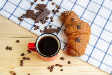 Ahşap bir arka planda kahve ve kruvasan. Yukarıdan gelen vize. Kahve çekirdeği