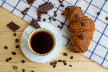 Ahşap bir arka planda kahve ve kruvasan. Yukarıdan manzara. Kahve çekirdeği