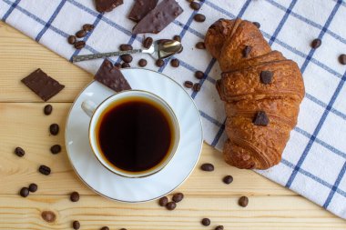 Ahşap bir arka planda kahve ve kruvasan. Yukarıdan manzara. Kahve çekirdeği