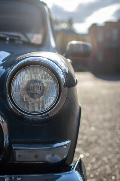 Close-up of a round headlight on an old car. On against the sun.