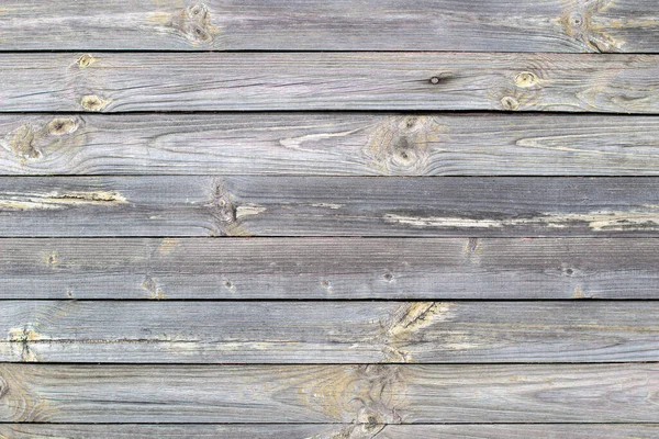 Wooden background made of old boards. The texture of an old rustic wooden fence made of flat processed boards. Wooden fence made of old boards with the inclusion of Knots. Background design