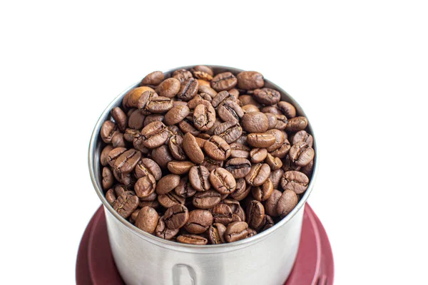 Un montón de granos de café en un molinillo de café de metal sobre un fondo blanco — Foto de Stock