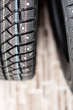 Yeni, siyah, çivili araba lastikleri. Güvenli sürüş, kışa hazırlık. Sarı, mavi ve kırmızı çizgili lastikler