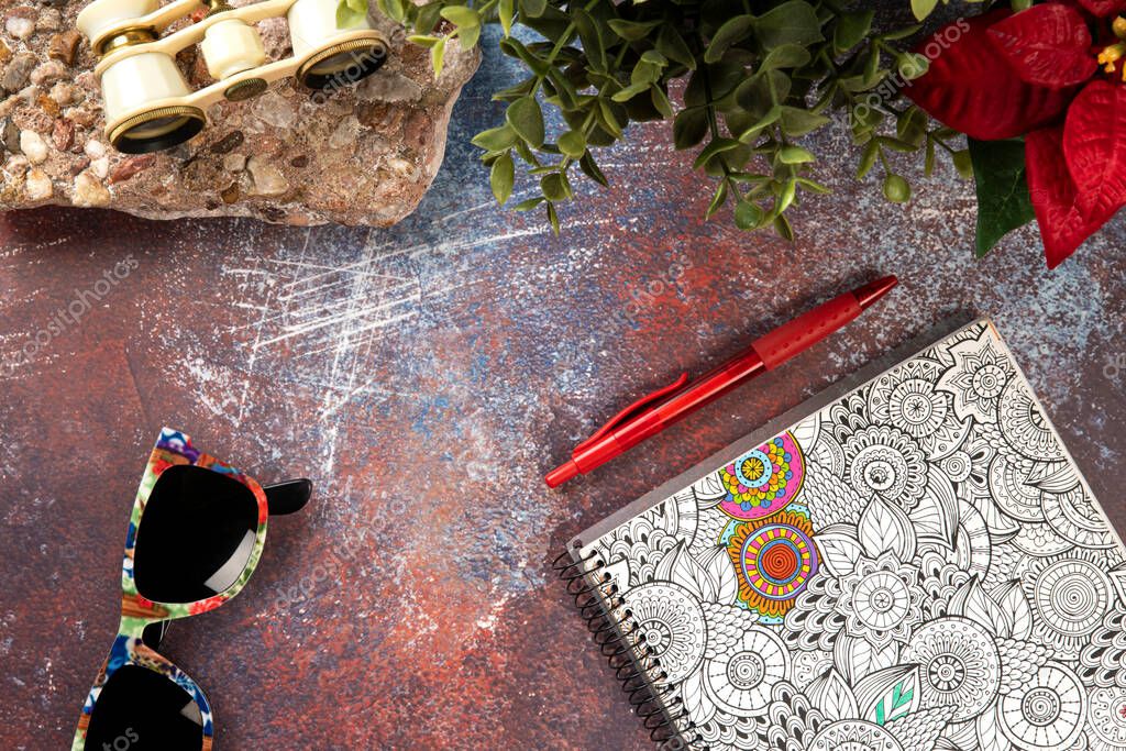 Old rusty metal texture for desk with a stone base, binoculars, sunglasses, notebook, pen and flower plants