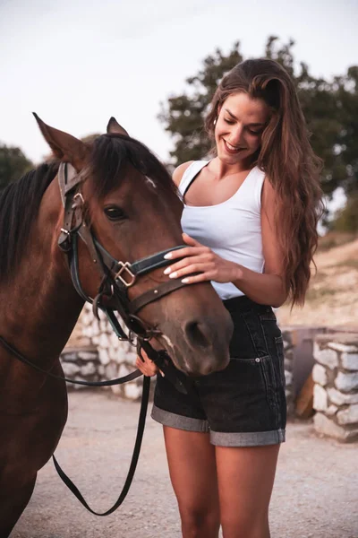 馬の笑顔と優しくそれに触れる若い女性 ファッションモデルの女の子と屋外写真 牧場のコンセプト写真 — ストック写真