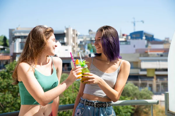 バルコニーでジュースを飲む2人の美しい十代の女の子と彼らの笑いアウトラウド ホームコンセプト — ストック写真