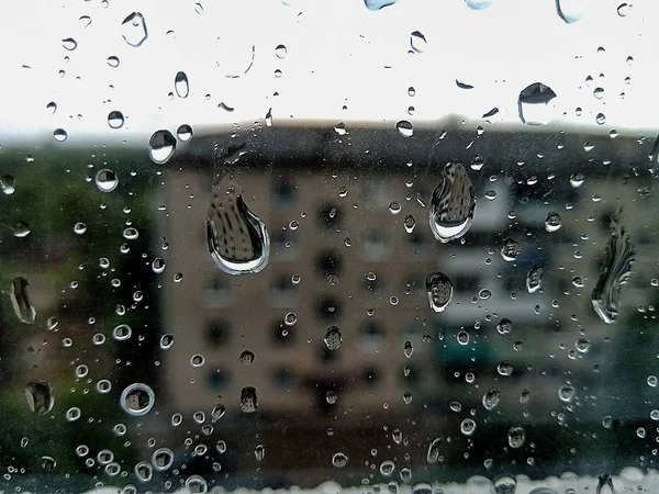 Raindrops on the morning through the glass with house background