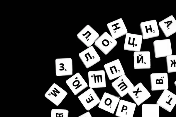 The letters of the Russian alphabet for a child\'s game scattered on a dark background close up