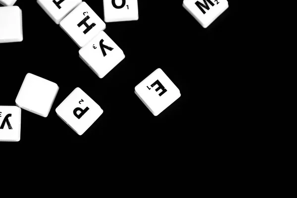 The letters of the Russian alphabet for a child\'s game scattered on a dark background close up