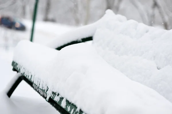 冬の市の公園で雪に覆われた長椅子にクローズ アップ — ストック写真