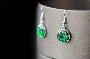 Damla reçine küpe karanlık bir arka plan üzerinde yeşil parıldıyor ile yakın çekim