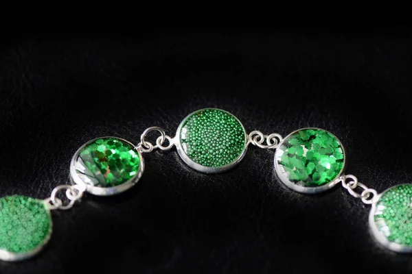 Resin bracelet with green sparkles on a dark background close up