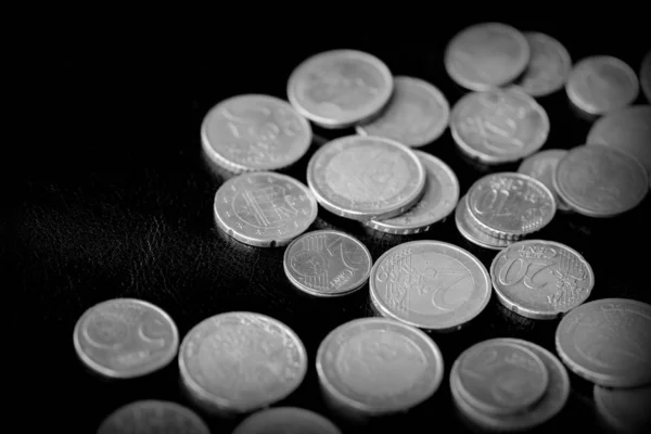 Euro coins scattered on a dark surface close up. Black and white