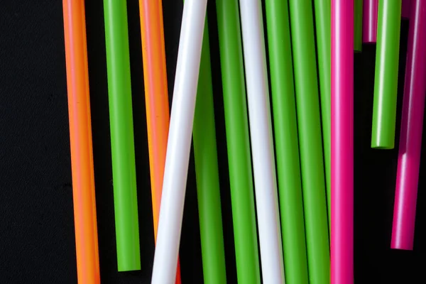 Colorful plastic straws on a dark background close up