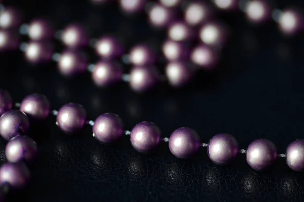 Long necklace of brown beads on a dark background close up