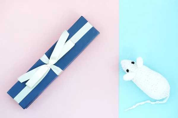 White crocheted rat and blue gift box on a paper background. Mouse symbol 2020 new year. Top view, copy space