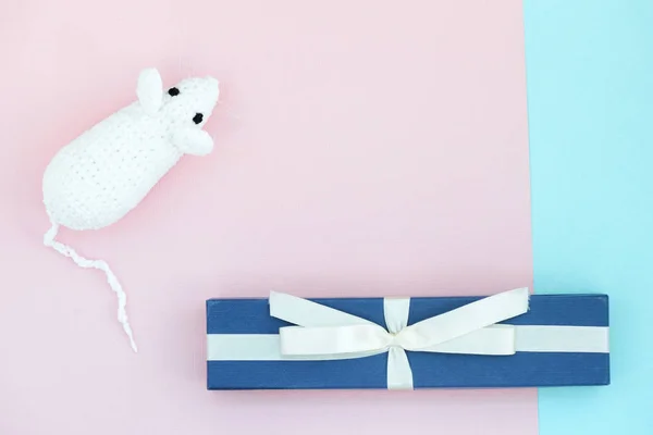 White crocheted rat and blue gift box on a paper background. Mouse symbol 2020 new year. Top view, copy space