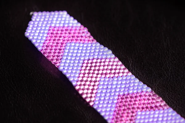 Beaded bracelet from beads of two colors on a dark background close-up