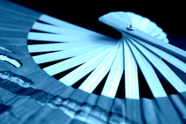 Vietnamese fan spread out on a dark background close-up. Blue color toned