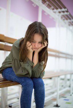 Mutsuz, depresif, elinde yüzüyle bankta oturan bir genç.