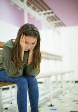 Mutsuz, depresif, elinde yüzüyle bankta oturan bir genç.